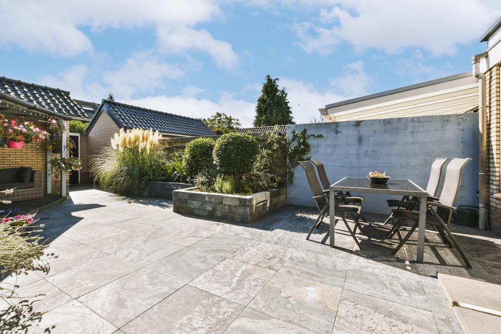 Outdoor kitchen flooring Florida with durable patio tile, dining furniture, and landscaped backyard space